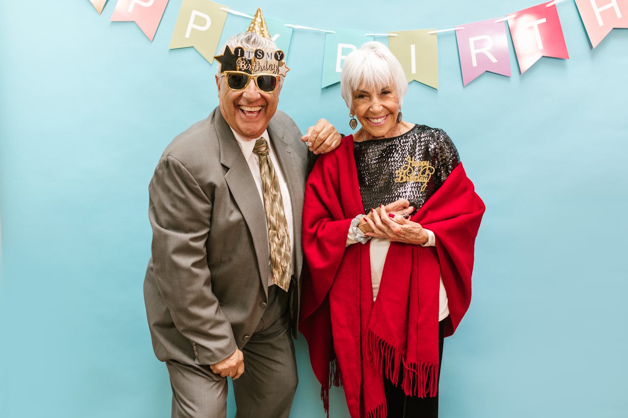 Smiling senior couple celebrating a birthday party with festive decor and joyful expressions.